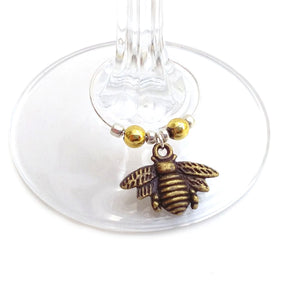 Bronze coloured metal wine charm clipped onto stem of wine glass