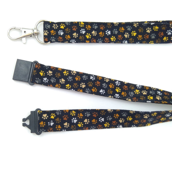 Close up of black fabric lanyard with paw prints showing black plastic safety buckle and metal swivel clasp